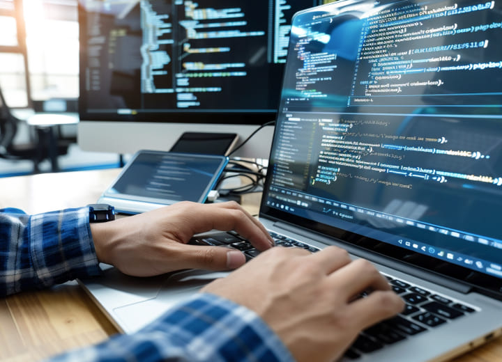 コードを書くエンジニアの手元とパソコン画面の画像